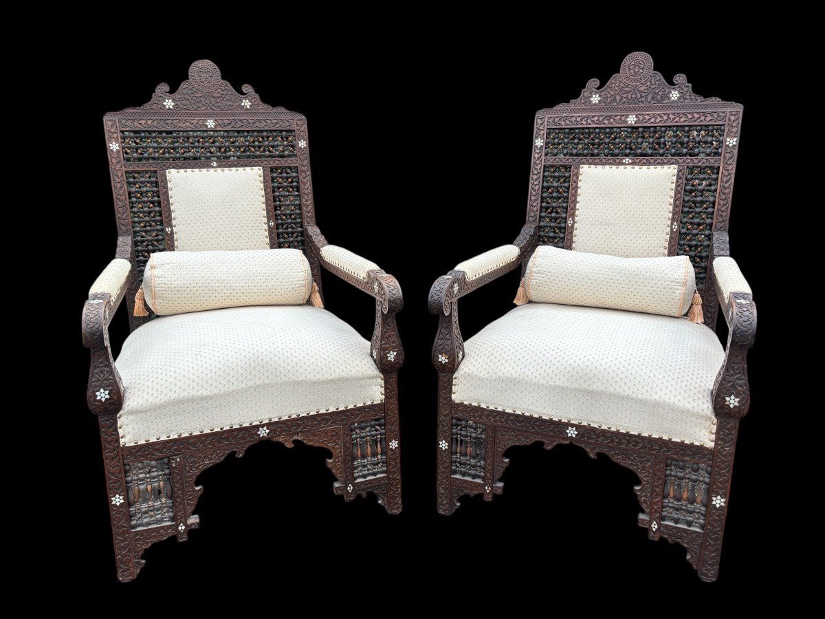 Pair of Carved Armchairs With Ebony And Mother Of Pearl Inlays. Syria, 19th century. Very decorative Orientalist armchairs upholstered in a beautiful fabric with cushion and scroll. Woodwork in good condition with a few chips and inlays due to age.