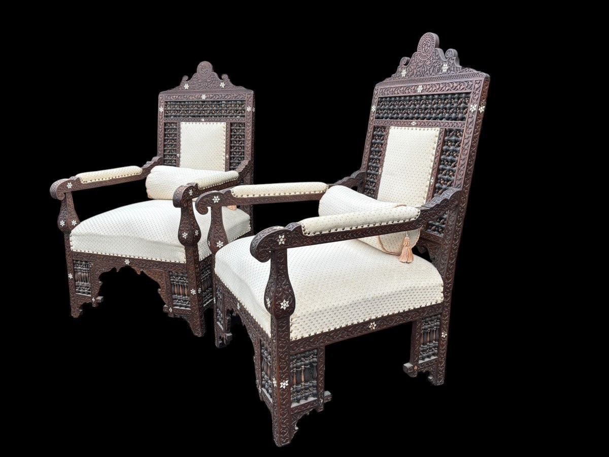 Pair of Carved Armchairs With Ebony And Mother Of Pearl Inlays. Syria, 19th century. Very decorative Orientalist armchairs upholstered in a beautiful fabric with cushion and scroll. Woodwork in good condition with a few chips and inlays due to age.