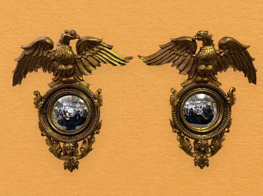 Pair of decorative ‘Eagles’ mirrors in gilded wood, late 19th century. Gilded wooden frame decorated with scrolls, paintings, a large gilded eagle and a convex mirror. Attractive pair of mirrors dating from around 1900.