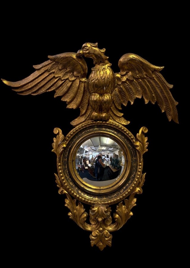 Pair of decorative ‘Eagles’ mirrors in gilded wood, late 19th century. Gilded wooden frame decorated with scrolls, paintings, a large gilded eagle and a convex mirror. Diameter of the curved mirror: 25 cm. 