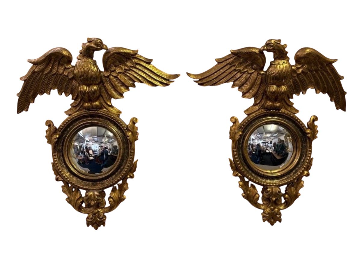 Pair of decorative ‘Eagles’ mirrors in gilded wood, late 19th century. Gilded wooden frame decorated with scrolls, paintings, a large gilded eagle and a convex mirror. Diameter of the curved mirror: 25 cm. 