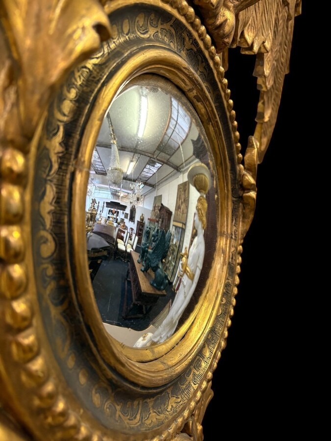 Pair of decorative ‘Eagles’ mirrors in gilded wood, late 19th century. Gilded wooden frame decorated with scrolls, paintings, a large gilded eagle and a convex mirror. Diameter of the curved mirror: 25 cm.