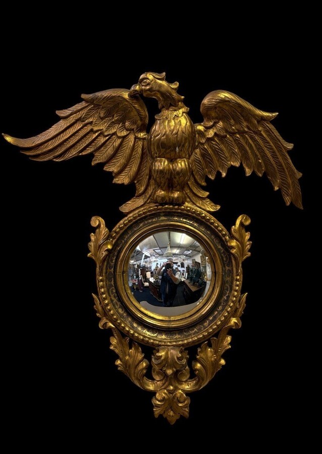 Pair of decorative ‘Eagles’ mirrors in gilded wood, late 19th century. Gilded wooden frame decorated with scrolls, paintings, a large gilded eagle and a convex mirror. Diameter of the curved mirror: 25 cm.