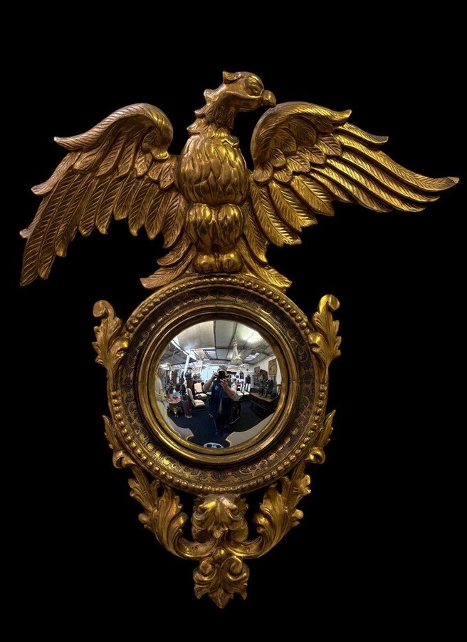Pair of decorative ‘Eagles’ mirrors in gilded wood, late 19th century. Gilded wooden frame decorated with scrolls, paintings, a large gilded eagle and a convex mirror. Diameter of the curved mirror: 25 cm.