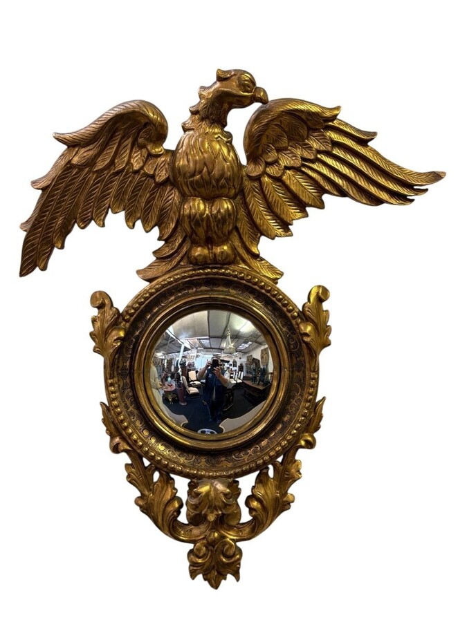 Pair of decorative ‘Eagles’ mirrors in gilded wood, late 19th century. Gilded wooden frame decorated with scrolls, paintings, a large gilded eagle and a convex mirror. Diameter of the curved mirror: 25 cm.