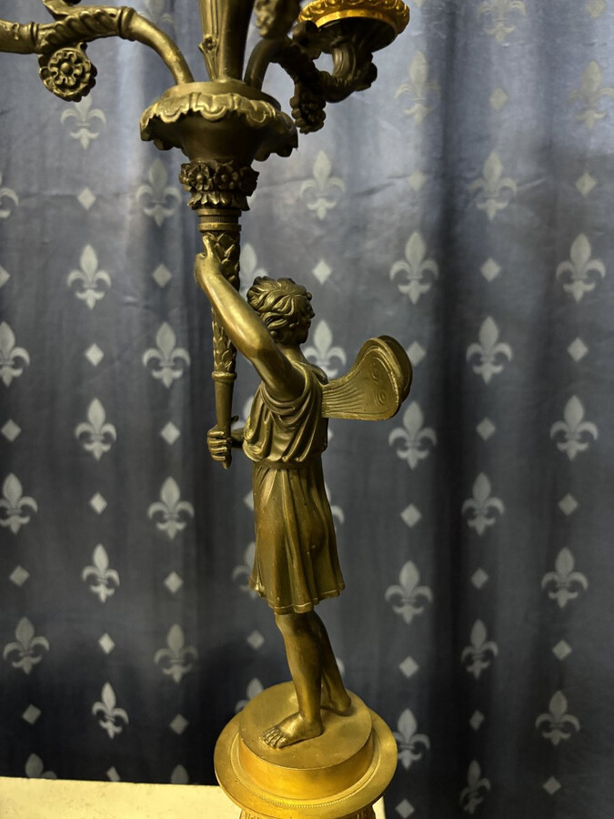 Pair of elegant bronze candelabra in the Empire style 19th century Pair of Empire period candelabra decorated with a winged man and a flame carrying a torch and four candles. They are both in very good condition 