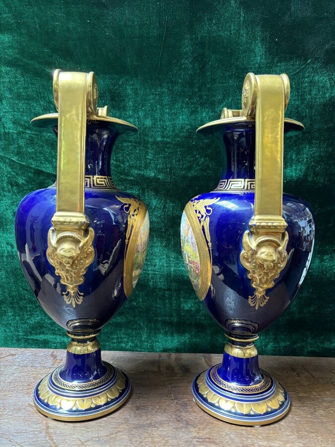 Pair of Empire style porcelain vases Sèvres , 20th Century Pair of vases with romantic paintings in blue and gilt tones. Signed by G.Etemod and underneath marked with Sèvres sign Dimensions : Height : 55 cm Width : 28 cm Diameter foot : 18 cm In