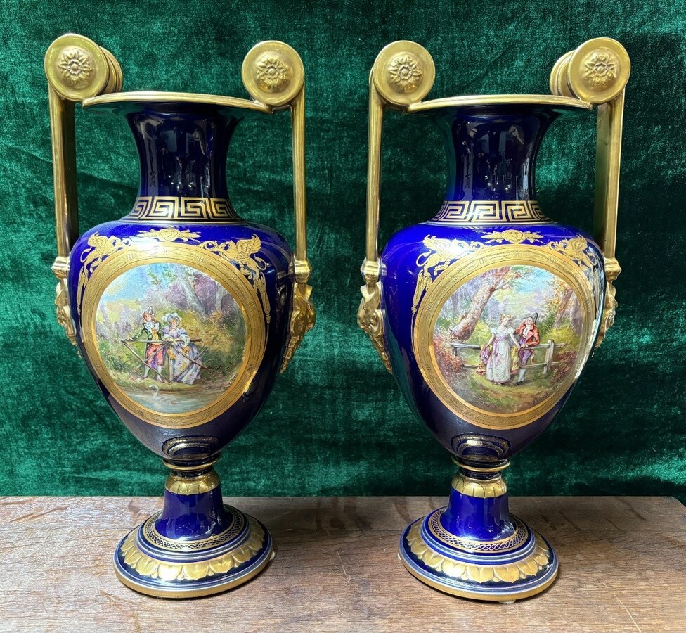 Pair of Empire style porcelain vases Sèvres , 20th Century Pair of vases with romantic paintings in blue and gilt tones. Signed by G.Etemod and underneath marked with Sèvres sign Dimensions : Height : 55 cm Width : 28 cm Diameter foot : 18 cm In