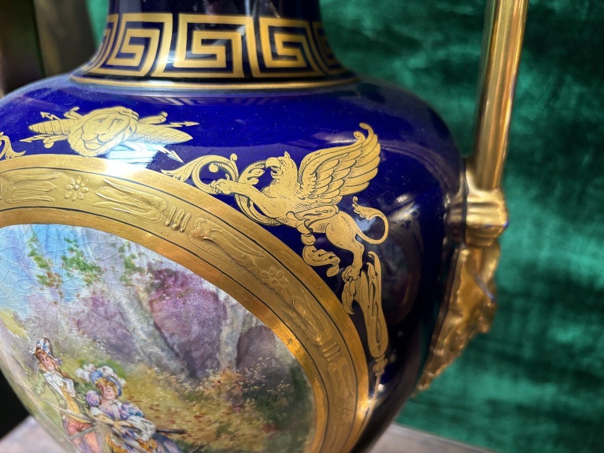 Pair of Empire style porcelain vases Sèvres , 20th Century Pair of vases with romantic paintings in blue and gilt tones. Signed by G.Etemod and underneath marked with Sèvres sign Dimensions : Height : 55 cm Width : 28 cm Diameter foot : 18 cm In