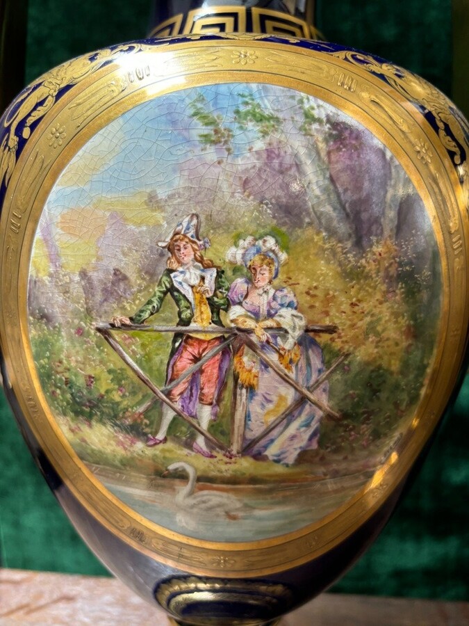 Pair of Empire style porcelain vases Sèvres , 20th Century Pair of vases with romantic paintings in blue and gilt tones. Signed by G.Etemod and underneath marked with Sèvres sign Dimensions : Height : 55 cm Width : 28 cm Diameter foot : 18 cm In