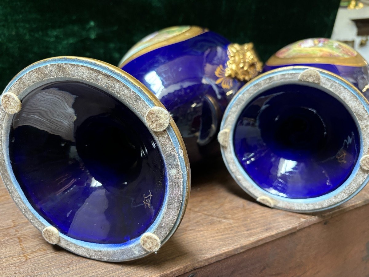 Pair of Empire style porcelain vases Sèvres , 20th Century Pair of vases with romantic paintings in blue and gilt tones. Signed by G.Etemod and underneath marked with Sèvres sign Dimensions : Height : 55 cm Width : 28 cm Diameter foot : 18 cm In