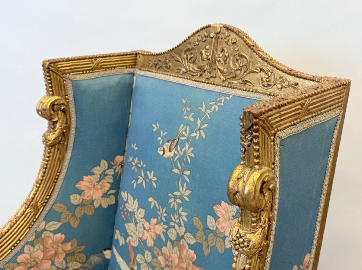 Pair of giltwood bergères in the Louis Seize style 1900 Decorative bergères adorned with garlands and carved ornaments and upholstered in a beautiful blue fabric with bird and flower motifs. The seat of one of the armchairs needs restoring!