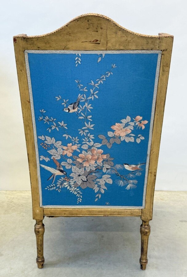 Pair of giltwood bergères in the Louis Seize style 1900 Decorative bergères adorned with garlands and carved ornaments and upholstered in a beautiful blue fabric with bird and flower motifs. The seat of one of the armchairs needs restoring!