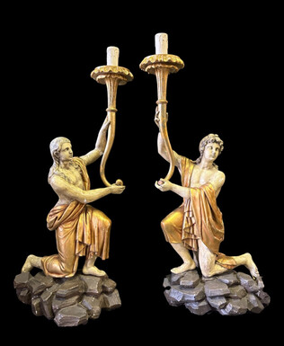 Pair of large 18th-century polychrome/gilded wooden sculptures/torch holders. 18th-century Italian decorative sculptures depicting two kneeling young men, draped in linen cloth and carrying a torch/candelabra. Both are in good condition 