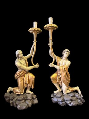 Pair of large 18th-century polychrome/gilded wooden sculptures/torch holders. 18th-century Italian decorative sculptures depicting two kneeling young men, draped in linen cloth and carrying a torch/candelabra. Both are in good condition with nor