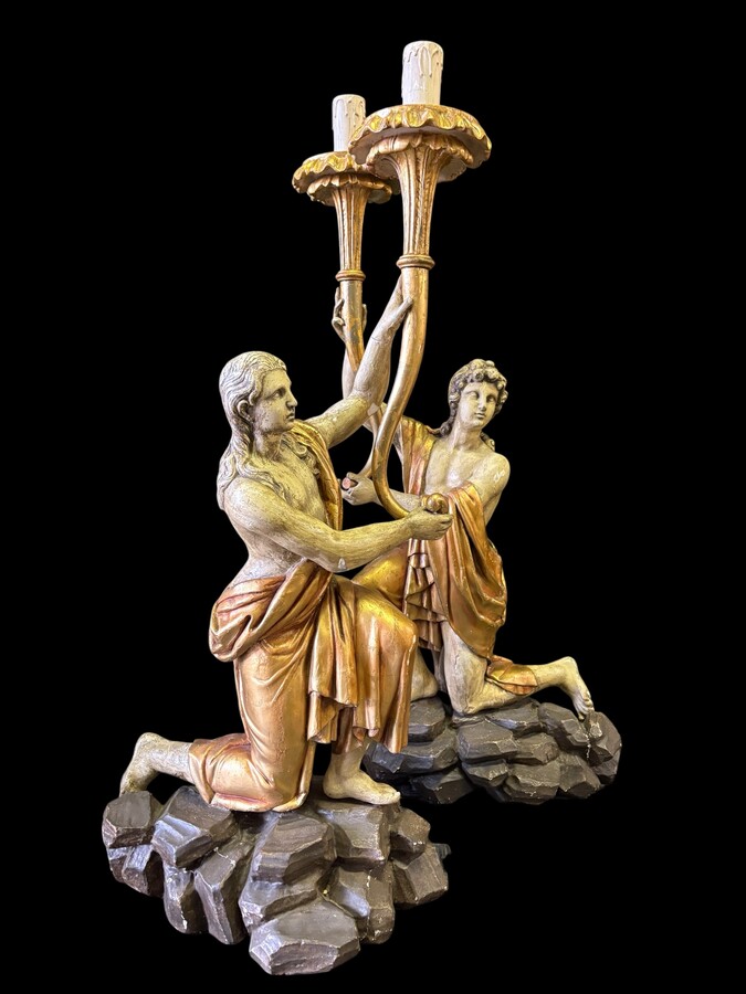 Pair of large 18th-century polychrome/gilded wooden sculptures/torch holders. 18th-century Italian decorative sculptures depicting two kneeling young men, draped in linen cloth and carrying a torch/candelabra. Both are in good condition with nor