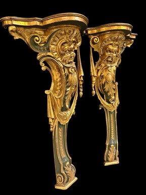 Pair of large, elegant 18th-century Italian wall consoles. Highly decorative consoles in gilded and patinated wood, adorned with a mythological head and decorated with drapery, volutes and ornaments. The top shelf is painted in faux marble.
