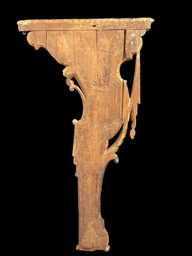 Pair of large, elegant 18th-century Italian wall consoles. Highly decorative consoles in gilded and patinated wood, adorned with a mythological head and decorated with drapery, volutes and ornaments. The top shelf is painted in faux marble. Italian,