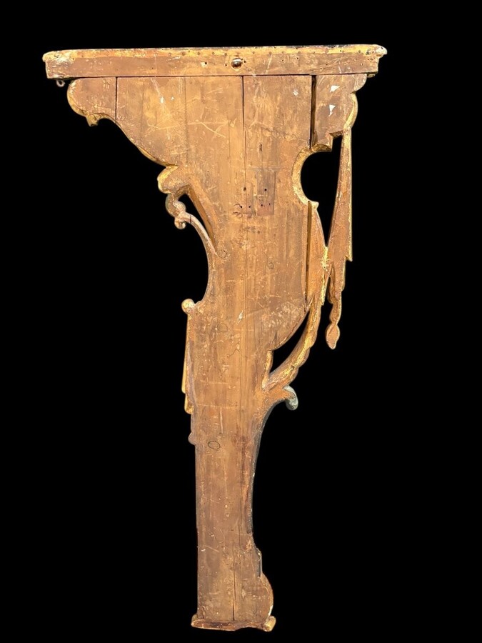 Pair of large, elegant 18th-century Italian wall consoles. Highly decorative consoles in gilded and patinated wood, adorned with a mythological head and decorated with drapery, volutes and ornaments. The top shelf is painted in faux marble. 