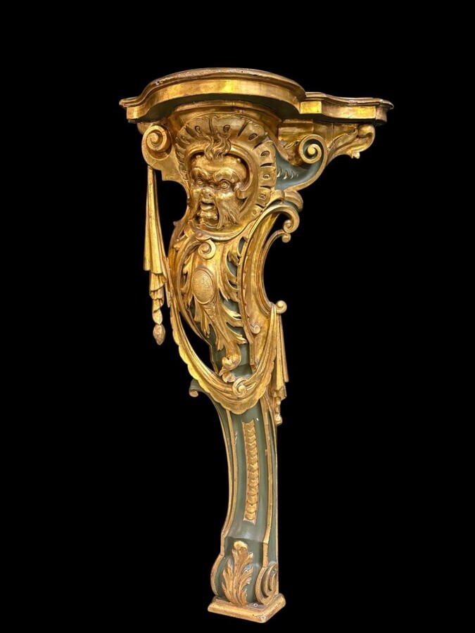 Pair of large, elegant 18th-century Italian wall consoles. Highly decorative consoles in gilded and patinated wood, adorned with a mythological head and decorated with drapery, volutes and ornaments. The top shelf is painted in faux marble. 