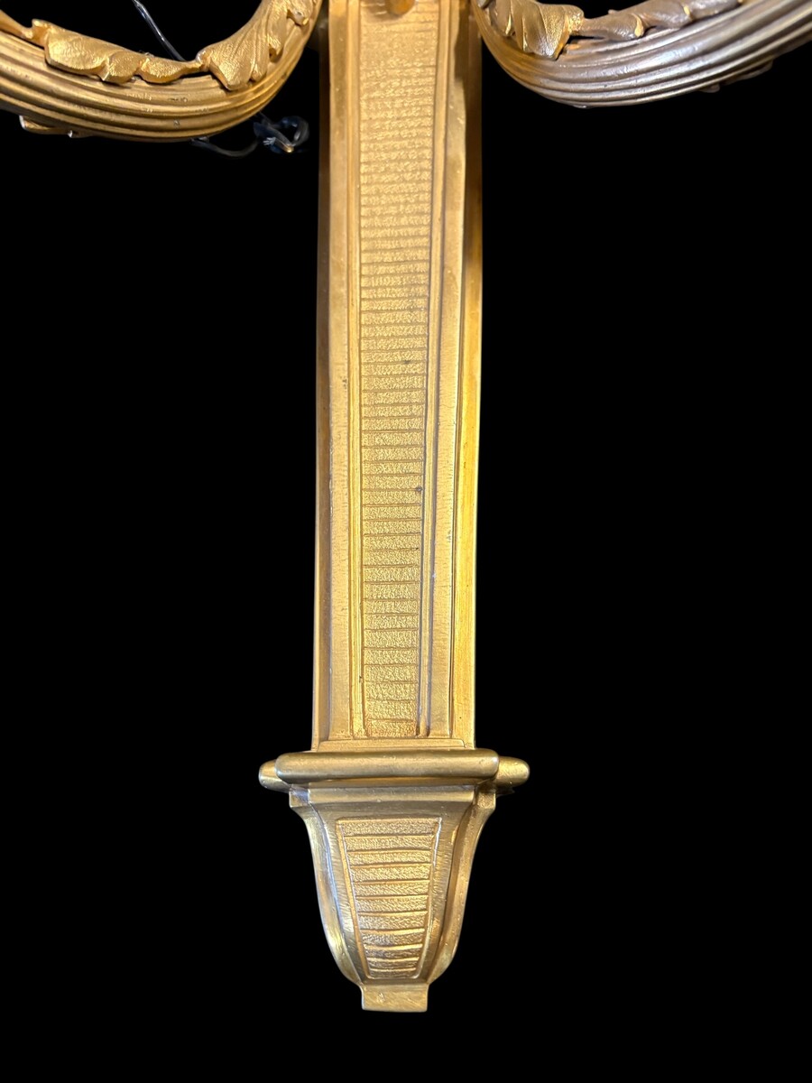 Pair of large Louis XVI-style bronze wall sconces, 19th century High-quality bronze wall sconces, chiselled, featuring an elegant design with two light points and a vase crowning the ensemble Dimensions: Height: 62 cm Width: 42 cm Depth: 22 cm