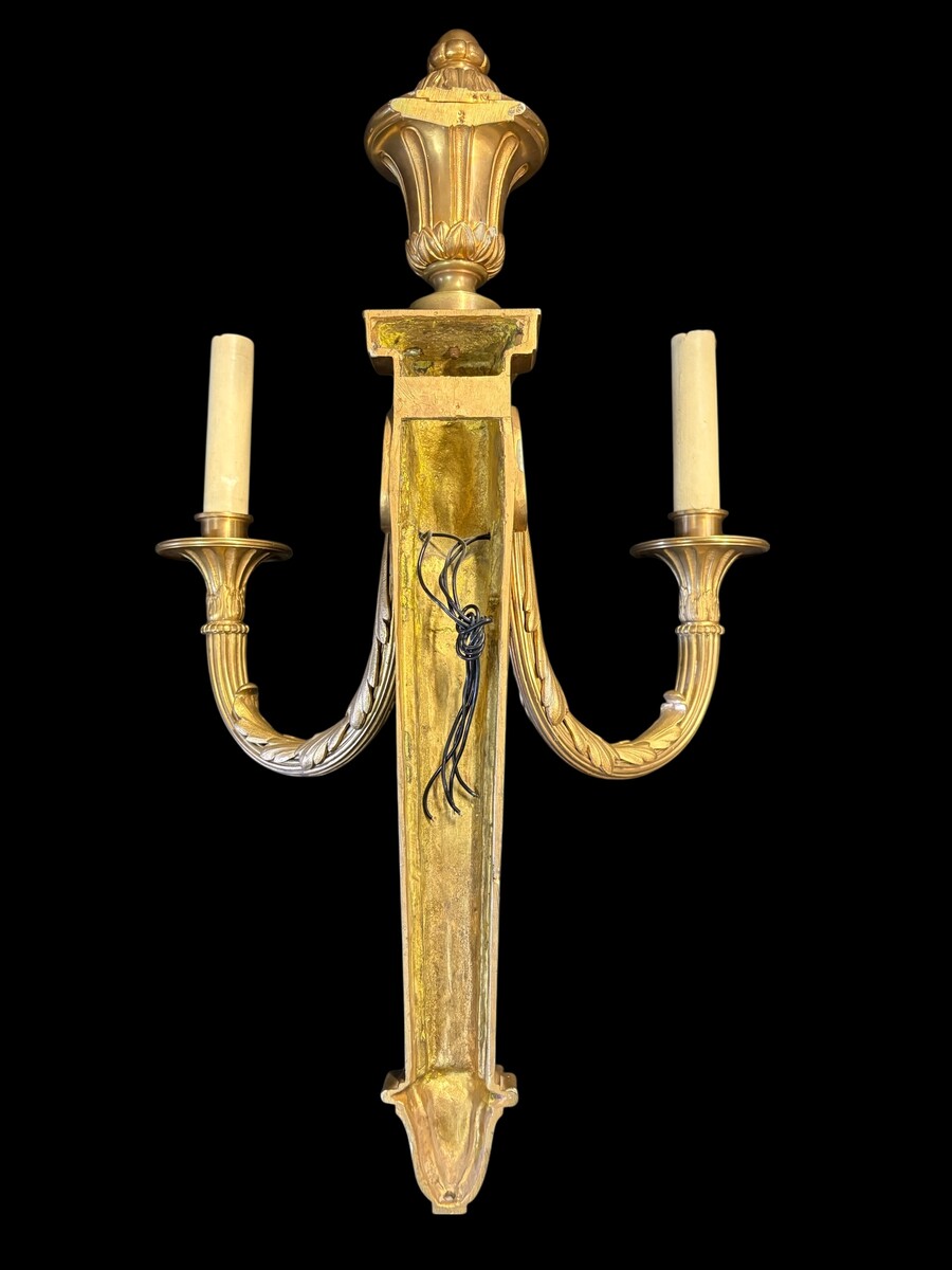 Pair of large Louis XVI-style bronze wall sconces, 19th century High-quality bronze wall sconces, chiselled, featuring an elegant design with two light points and a vase crowning the ensemble Dimensions: Height: 62 cm Width: 42 cm Depth: 22 cm