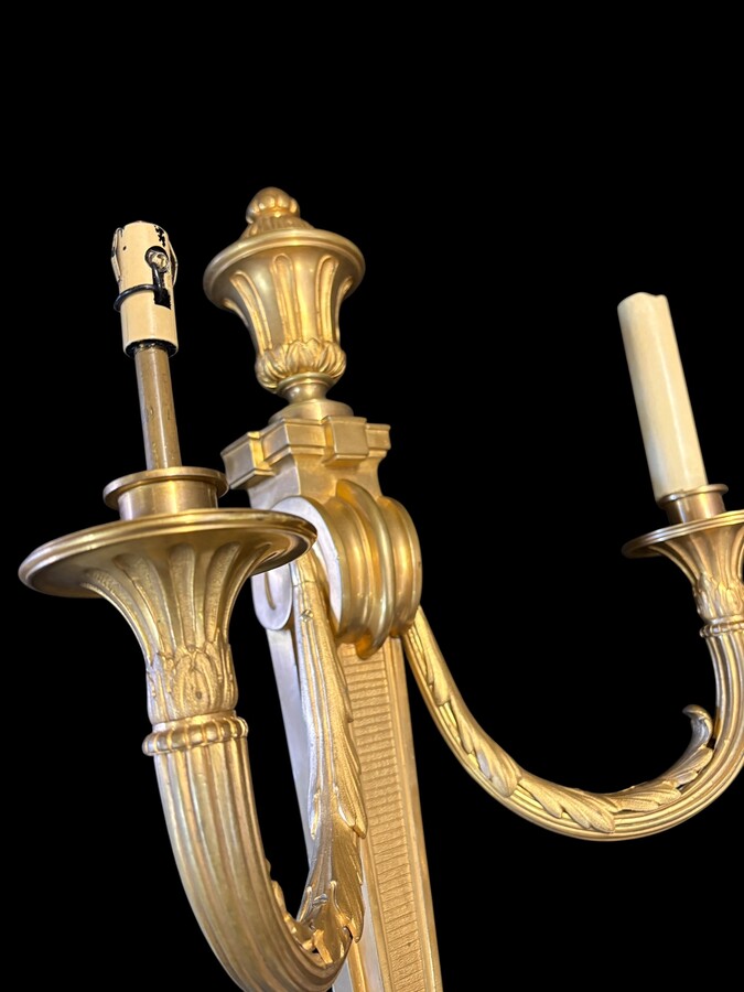 Pair of large Louis XVI-style bronze wall sconces, 19th century High-quality bronze wall sconces, chiselled, featuring an elegant design with two light points and a vase crowning the ensemble Dimensions: Height: 62 cm Width: 42 cm Depth: 22 cm
