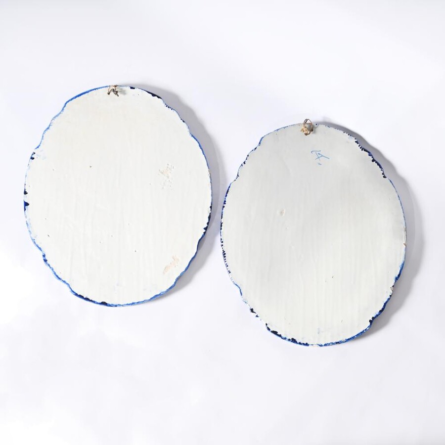 Pair of large Makkum earthenware wall plates Highly decorative blue and white earthenware wall plates depicting Dutch landscapes with windmills, water, boats, houses and animals. Fitted with a hanging loop and marked on the back. 