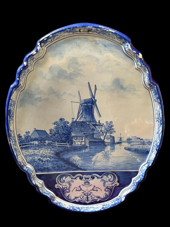 Pair of large Makkum earthenware wall plates Highly decorative blue and white earthenware wall plates depicting Dutch landscapes with windmills, water, boats, houses and animals. Fitted with a hanging loop and marked on the back. 