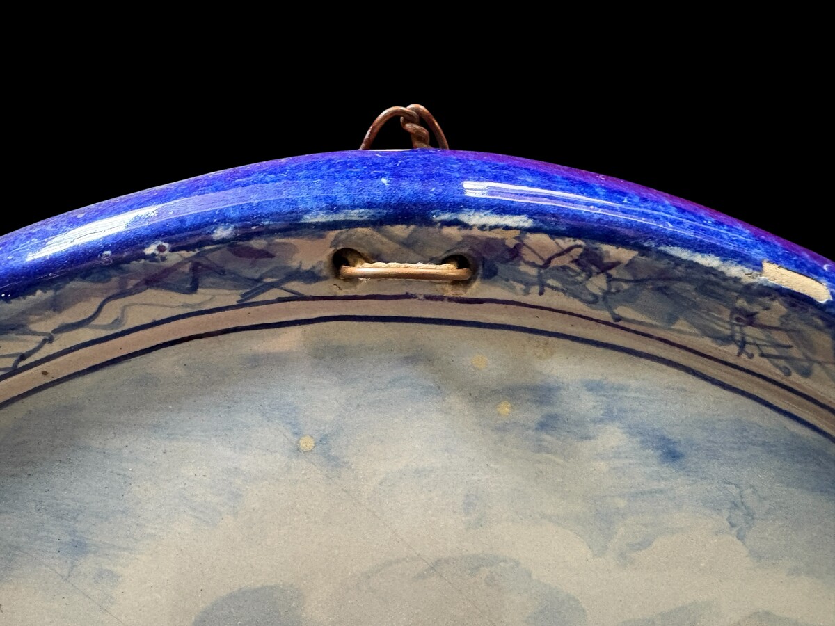 Pair of large Makkum earthenware wall plates Highly decorative blue and white earthenware wall plates depicting Dutch landscapes with windmills, water, boats, houses and animals. Fitted with a hanging loop and marked on the back. 