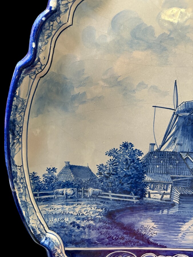 Pair of large Makkum earthenware wall plates Highly decorative blue and white earthenware wall plates depicting Dutch landscapes with windmills, water, boats, houses and animals. Fitted with a hanging loop and marked on the back. 
