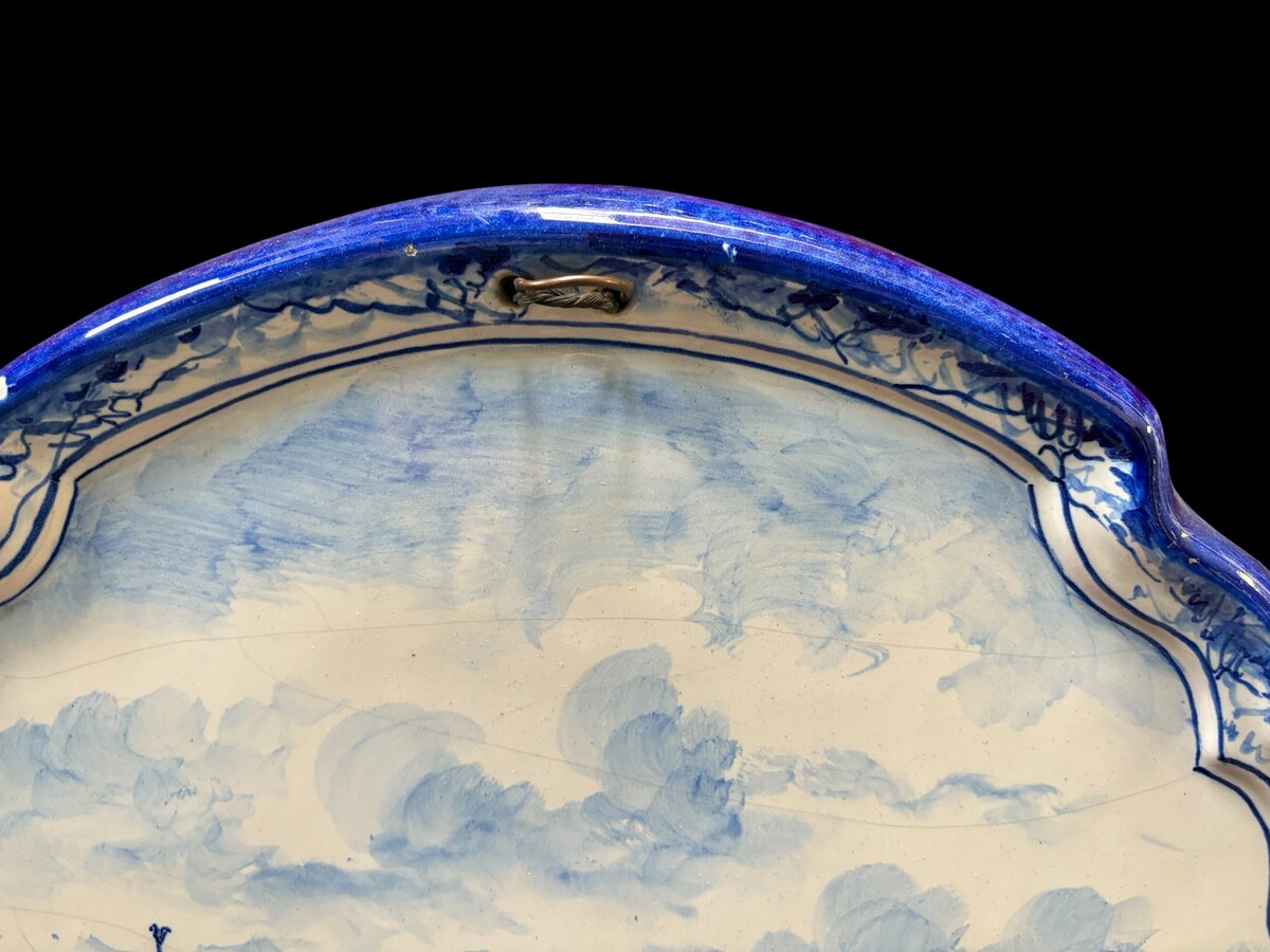 Pair of large Makkum earthenware wall plates Highly decorative blue and white earthenware wall plates depicting Dutch landscapes with windmills, water, boats, houses and animals. Fitted with a hanging loop and marked on the back. 