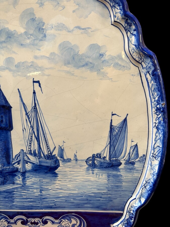 Pair of large Makkum earthenware wall plates Highly decorative blue and white earthenware wall plates depicting Dutch landscapes with windmills, water, boats, houses and animals. Fitted with a hanging loop and marked on the back. 