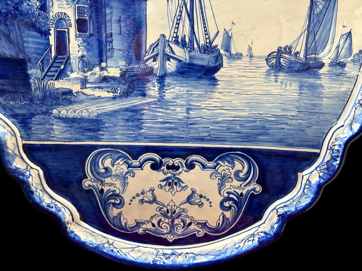 Pair of large Makkum earthenware wall plates Highly decorative blue and white earthenware wall plates depicting Dutch landscapes with windmills, water, boats, houses and animals. Fitted with a hanging loop and marked on the back. 