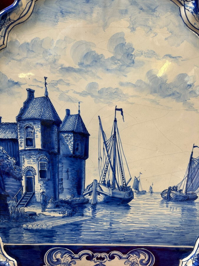 Pair of large Makkum earthenware wall plates Highly decorative blue and white earthenware wall plates depicting Dutch landscapes with windmills, water, boats, houses and animals. Fitted with a hanging loop and marked on the back.