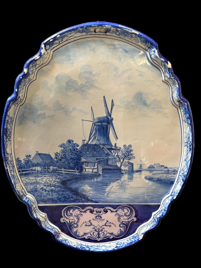 Pair of large Makkum earthenware wall plates Highly decorative blue and white earthenware wall plates depicting Dutch landscapes with windmills, water, boats, houses and animals. Fitted with a hanging loop and marked on the back.
