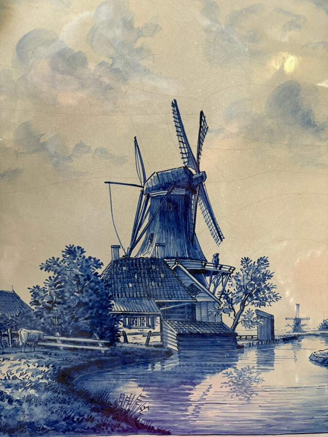 Pair of large Makkum earthenware wall plates Highly decorative blue and white earthenware wall plates depicting Dutch landscapes with windmills, water, boats, houses and animals. Fitted with a hanging loop and marked on the back.