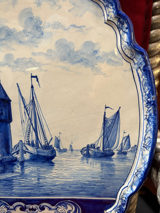 Pair of large Makkum earthenware wall plates Highly decorative blue and white earthenware wall plates depicting Dutch landscapes with windmills, water, boats, houses and animals. Fitted with a hanging loop and marked on the back.
