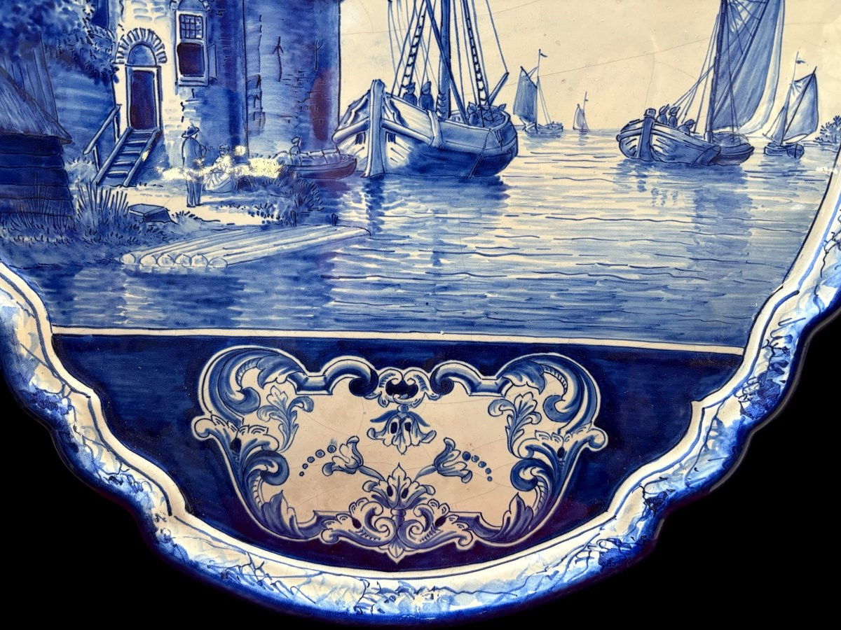 Pair of large Makkum earthenware wall plates Highly decorative blue and white earthenware wall plates depicting Dutch landscapes with windmills, water, boats, houses and animals. Fitted with a hanging loop and marked on the back.