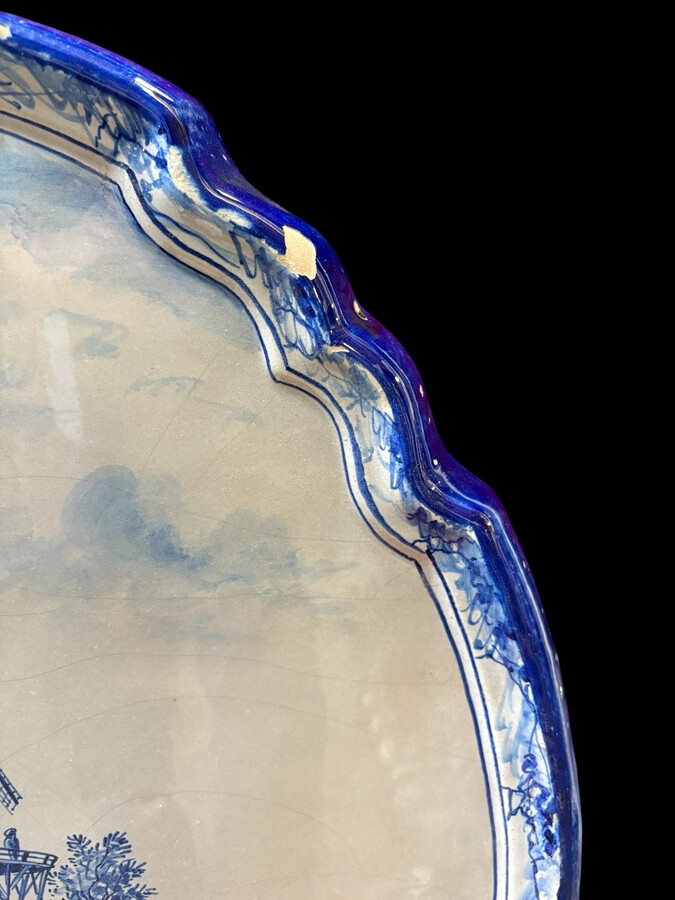 Pair of large Makkum earthenware wall plates Highly decorative blue and white earthenware wall plates depicting Dutch landscapes with windmills, water, boats, houses and animals. Fitted with a hanging loop and marked on the back.