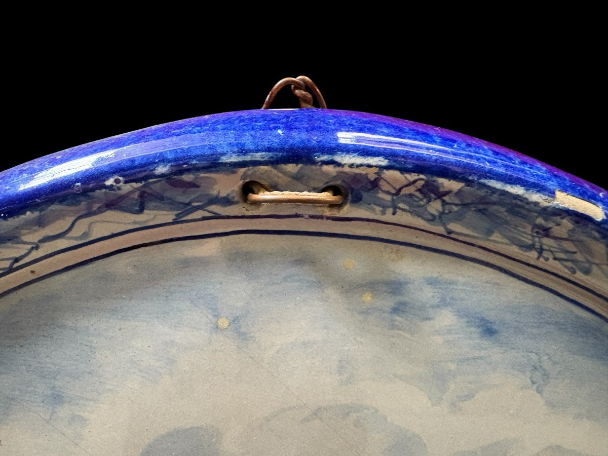 Pair of large Makkum earthenware wall plates Highly decorative blue and white earthenware wall plates depicting Dutch landscapes with windmills, water, boats, houses and animals. Fitted with a hanging loop and marked on the back.