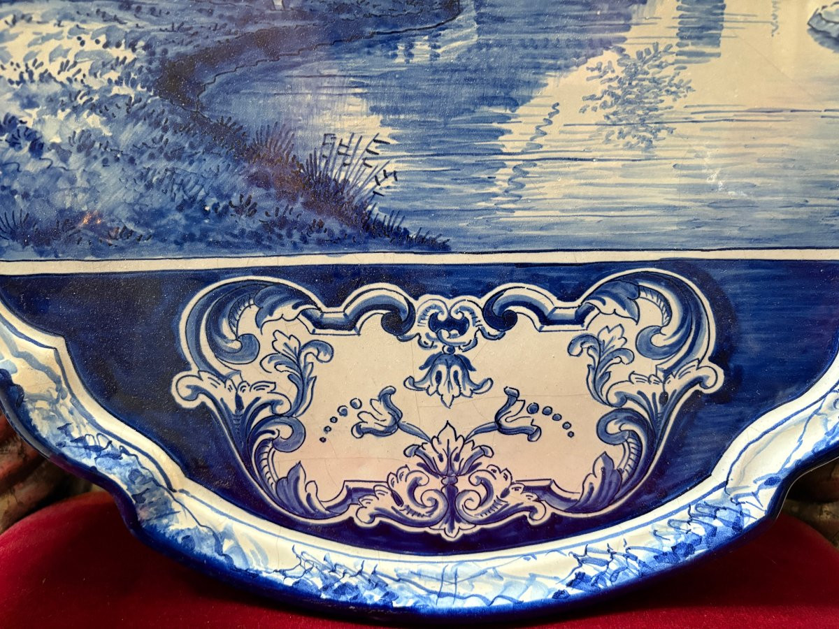 Pair of large Makkum earthenware wall plates Highly decorative blue and white earthenware wall plates depicting Dutch landscapes with windmills, water, boats, houses and animals. Fitted with a hanging loop and marked on the back.