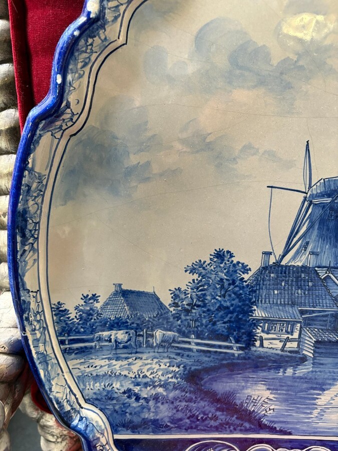 Pair of large Makkum earthenware wall plates Highly decorative blue and white earthenware wall plates depicting Dutch landscapes with windmills, water, boats, houses and animals. Fitted with a hanging loop and marked on the back.