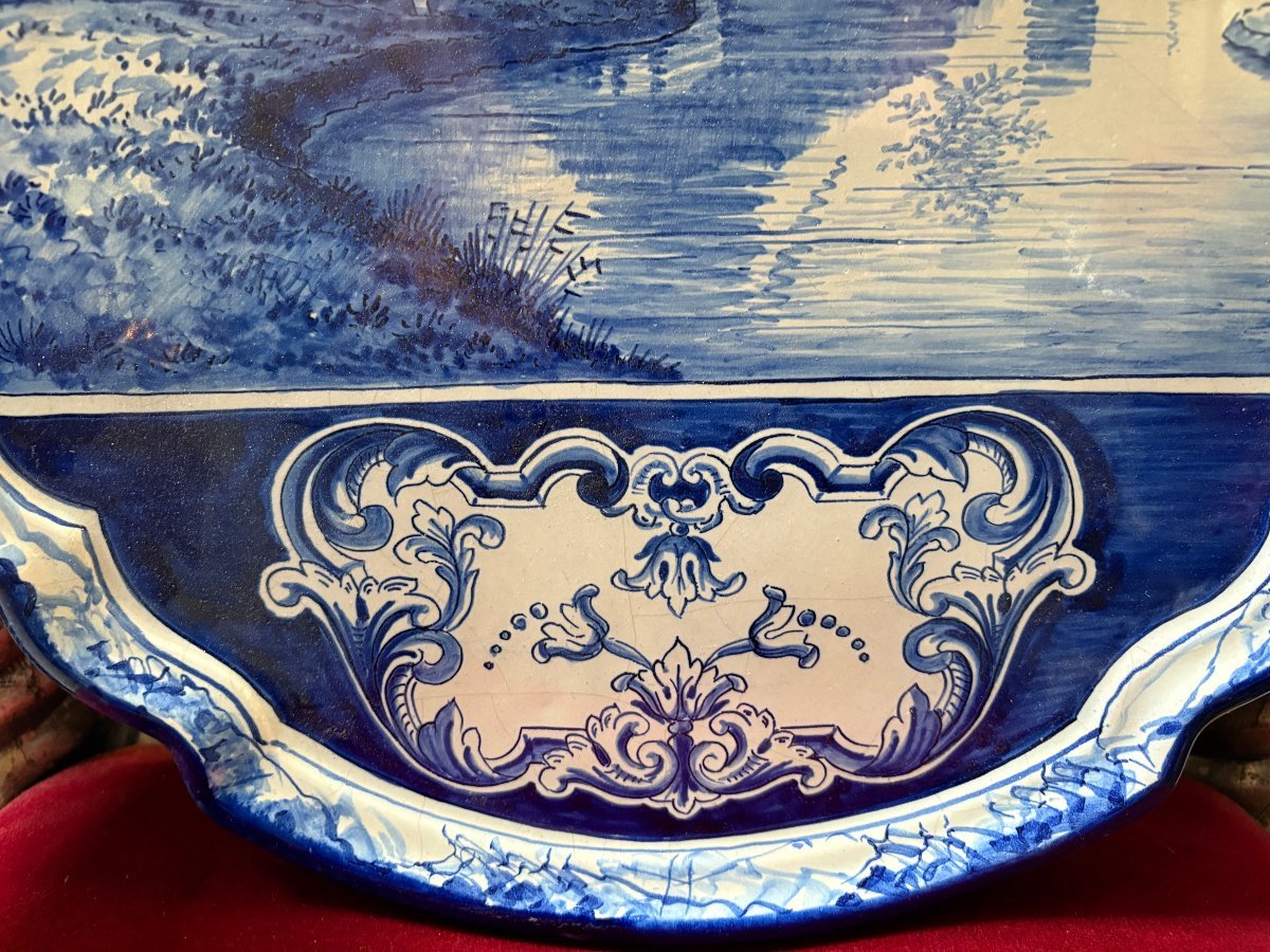 Pair of large Makkum earthenware wall plates Highly decorative blue and white earthenware wall plates depicting Dutch landscapes with windmills, water, boats, houses and animals. Fitted with a hanging loop and marked on the back.