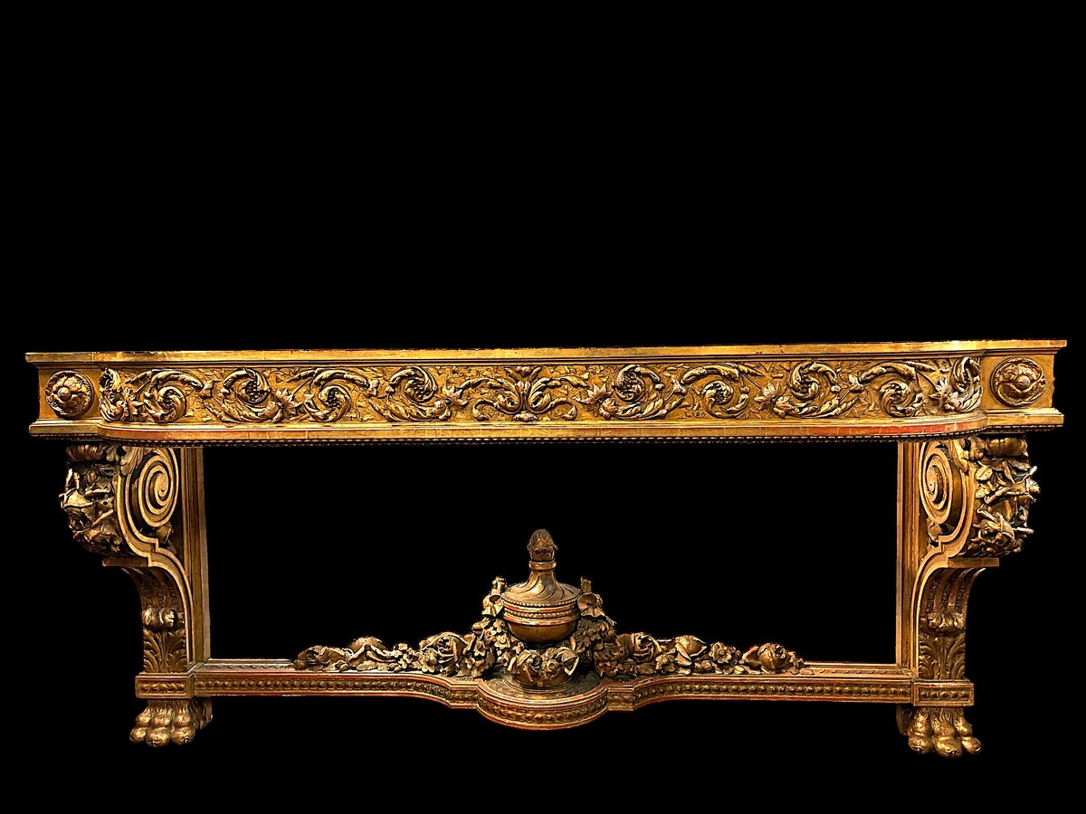 Very large Louis XVI style console table (230 cm) in gilded wood from the 19th century. High-quality console table entirely carved in wood, decorated with gilded motifs, floral scrolls, a large decorative vase in its lower section.