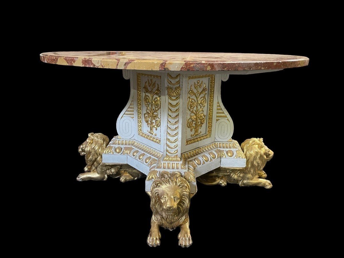 White and Gold Carved Wooden Table With Round Top In Breche d'Alep Marble. A white and gold carved wooden centre table with a round Breche d'Alep marble top resting on a central quadrangular shaft underlined by four inverted consoles and panels.